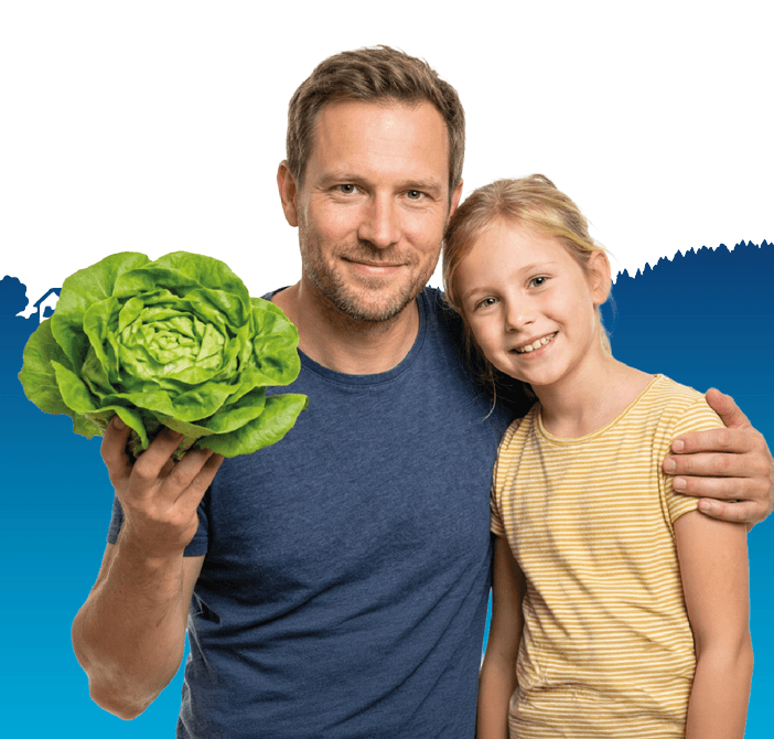 Vater und Tochter präsentieren den frischen Salat, welchen sie von lokal Produzierenden gekauft haben.